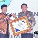 Foto : Bupati Lamongan Yuhronur Efendi berdiri di atas panggung menerima plakat penghargaan dari Wagub Jatim Emil Dardak