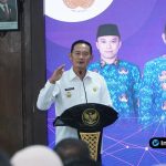 Foto : Bupati Lamongan Yuhronur Efendi berdiri di podium berbicara dalam seminar, dengan latar belakang spanduk besar bertuliskan Sosialisasi UU No. 1 Tahun 2023 tentang KUHP.