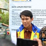 Foto : Close-up Bupati Yuhronur Efendi menyampaikan pidato dengan latar belakang jalan baru dan masyarakat yang hadir.