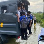 Foto : Kendaraan dinas Polres Lamongan (mobil patrolidouble cabin) melintasi jalan yang tergenang air dengan beberapa siswa di dalamnya.