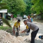 Foto : Suasana kerja bakti dengan beberapa orang warga dan polisi saling membantu mengangkut material atau meratakan jalan.
